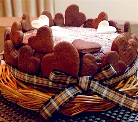 A Heart Shaped Chocolate Cake On A Wicker Basket With Ribbon Around The Edges And Hearts Cut Out