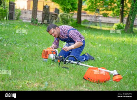 One Gardener Mowing Grass Fixing Brush Cutter Problem Stock Photo Alamy