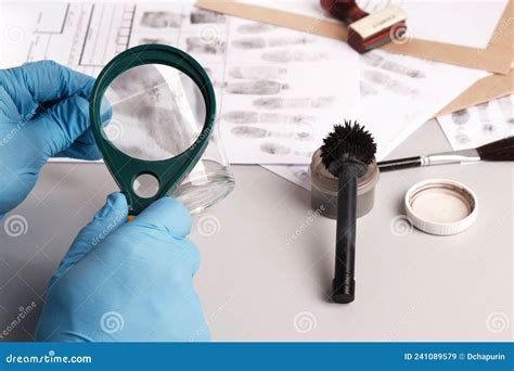 Forensic Expert Using A Magnifying Glass Examines Fingerprints On