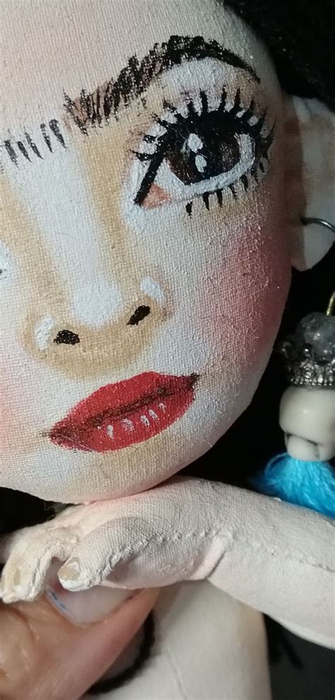 A Close Up Of A Person Holding A Doll With Makeup On It S Face