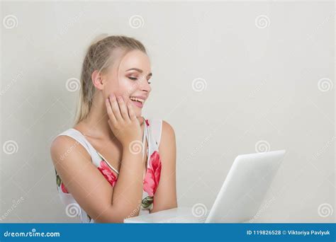 Pretty Cheerful Blonde Woman Looking Into Laptop Posing On The Stock