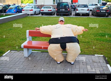 Boy In Inflatable Sumo Wrestler Suit Sitting On Bench On Territory Near