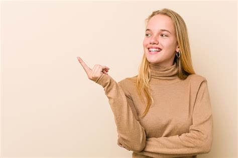 Mujer adolescente linda y natural sonriendo alegremente señalando con