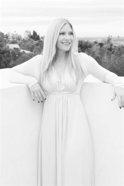 a woman in a long white dress leaning against a wall with her hands on ...