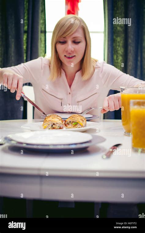 Pretty Blonde Woman In A Pink Shirt Eating At Home A Fork And Knife