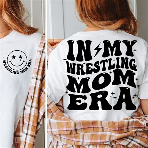 A Woman Wearing A White Shirt That Says In My Wrestling Mom Era On The Back