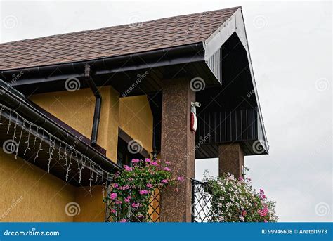 Del Av Balkongen Med Blommor Och Ett Belagt Med Tegel Tak Mot Himlen