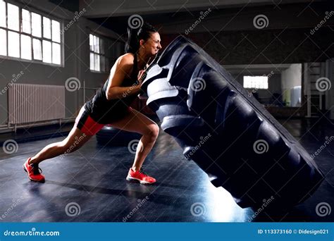 Side View Of Strong Woman Pushing Tire During Workout Stock Photo