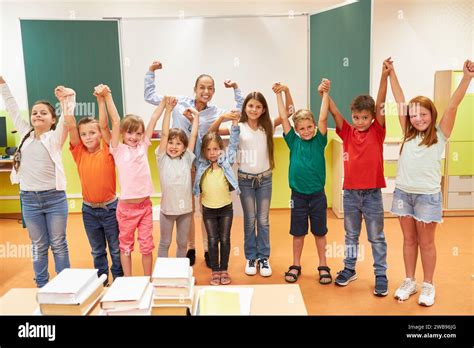 Excited female teacher cheering with diverse students while standing in ...