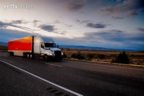 Long Haul Semi Truck Speeding Down A Four Lane Highway To Delivery