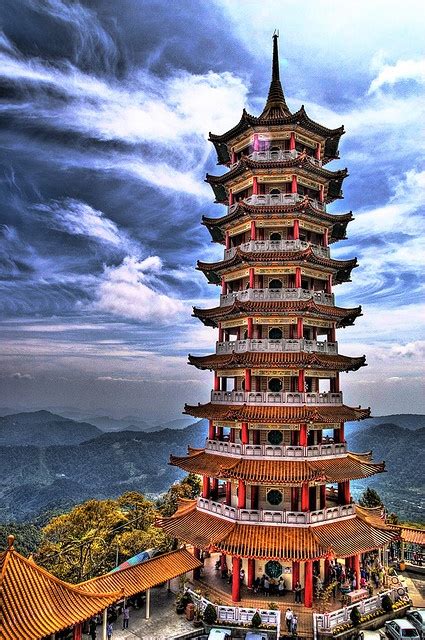 A Tall Pagoda Tower Sitting On Top Of A Lush Green Hillside Under A