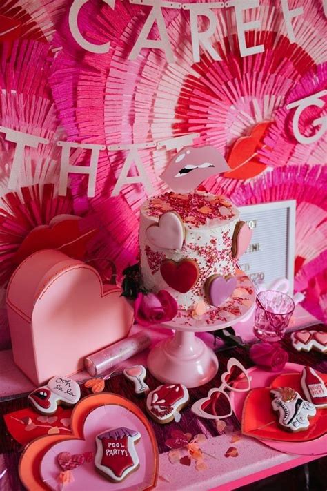 A Pink Table Topped With A Cake And Lots Of Cupcakes