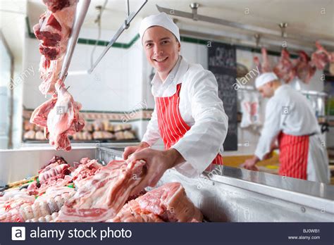 Smiling Butcher Arranging Meat In Display Case Stock Photo Royalty