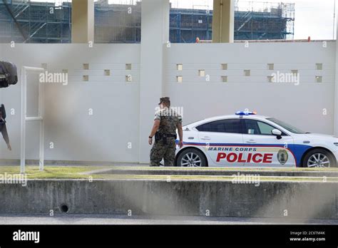 Military Police officer walking by a police car at the main gate of U.S. Marine Corps Camp ...