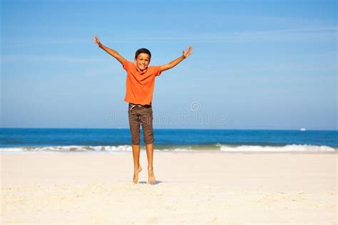 Glad Pojke Hoppar Upp Med Utspridda Händer över Havsstranden Arkivfoto