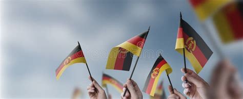 A Group Of People Holding Small Flags Of The DDR In Their Hands Stock