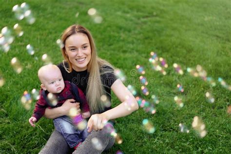 Young Caucasian Mother Inflates Soap Bubbles With Her Little Son In A