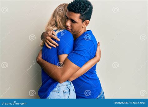 Young Interracial Couple Wearing Casual Clothes Hugging Oneself Happy