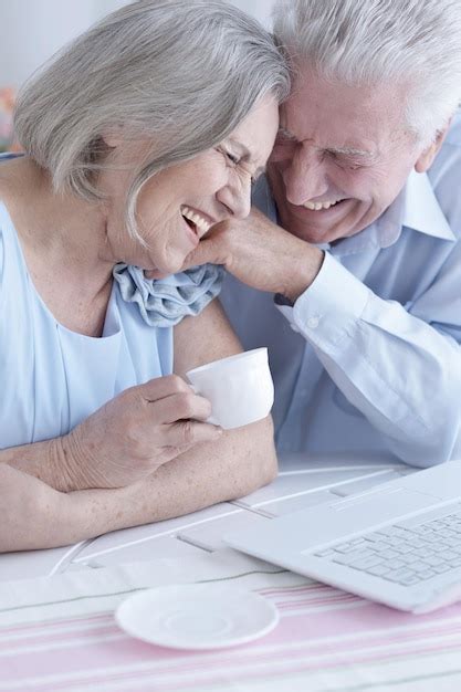 Retrato de una feliz pareja de ancianos bebiendo té y usando una laptop