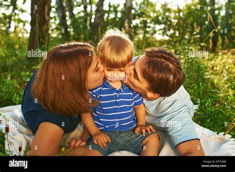 Happy parents kissing their child outdoors Stock Photo - Alamy