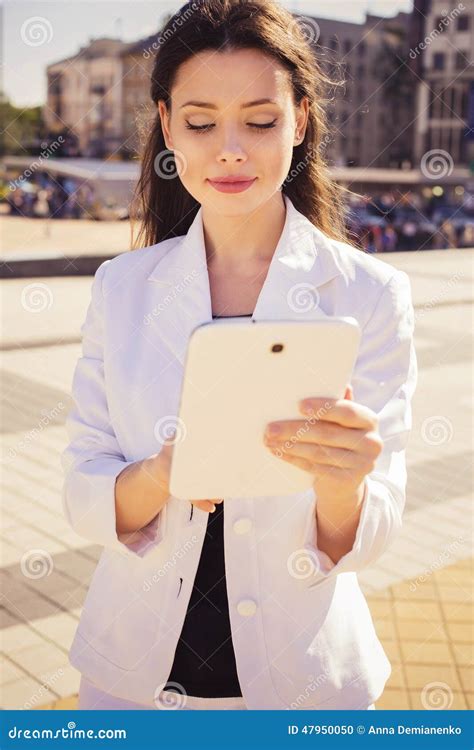 Beautiful Brunette Business Woman In White Suit Working On A Tab Stock