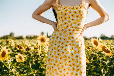 Young Caucasian Woman In Sunflower Dress Standing In Sunflower Field