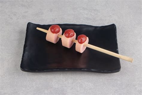 Free Photo Stick Of Sausages With Ketchup On Black Plate