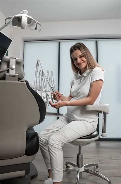 A Dentist In A Modern Medical Center Looks At The Camera And Prepares