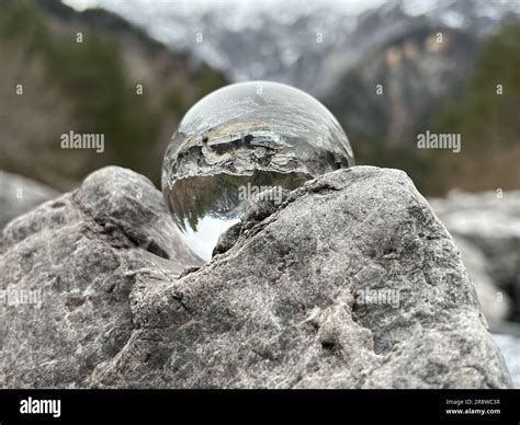 Lensball, crystal ball on rocks, reflecting an alpine creek, in the background Montafon's famous ...