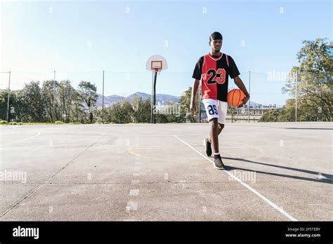 Serious African American Male Streetball Player In Uniform Walking With