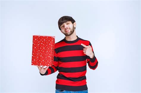 Hombre De Camisa A Rayas Rojas Sosteniendo Una Caja De Regalo Roja Y