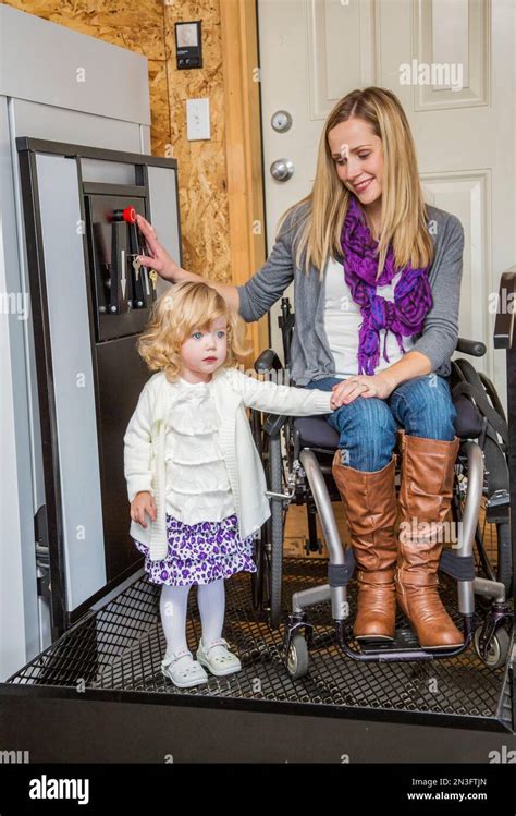 Young Disabled Mother With Her Daughter Using A Wheelchair Powered Device To Assist With