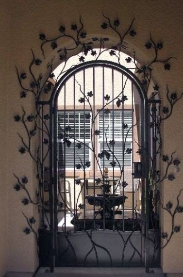 An Iron Gate With Flowers On It In Front Of A Window