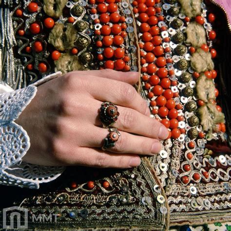 A Close Up Of A Person S Hand Holding An Orange Beaded Jacket And Ring