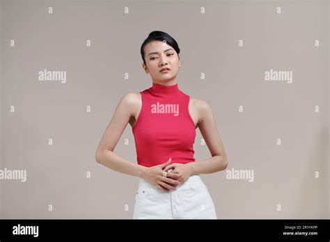 Asian Woman Suffering From Stomach Pain On Beige Background Stock Photo