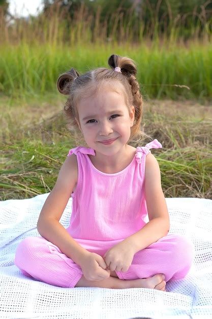 Una niña linda está sentada en la hierba en el campo moda belleza