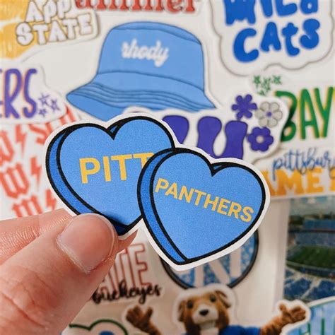 A Hand Holding Up Two Stickers With The Words Pitt S On Them In Front