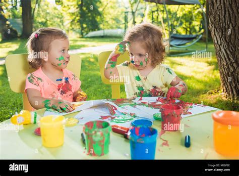 Two Year Old Girls Painting With Poster Paintings Together Against