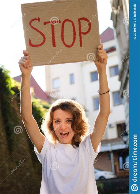 Young Protesting Woman In White Shirt And Jeans Holds Protest Sign