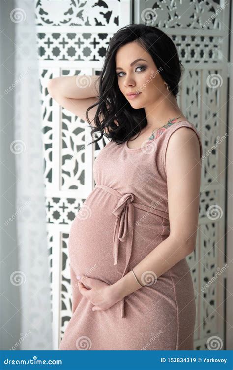 Women`s Health And Pregnancy A Beautiful Pregnant Woman In A Tender Pink Dress Is Standing Near