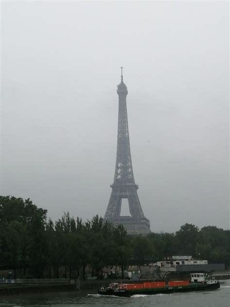 The Eiffel Tower Towering Over The City Of Paris On A Foggy Day