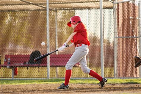 A Girl Batting Hits The Baseball In A Baseball Game By Stocksy