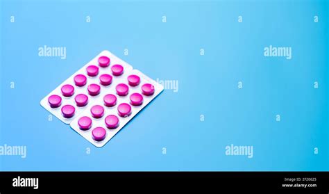 Round Pink Tablets Pills In Blister Pack On Blue Background With Space