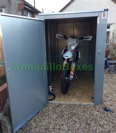 a motorcycle is parked in the back of a metal storage shed with its door open