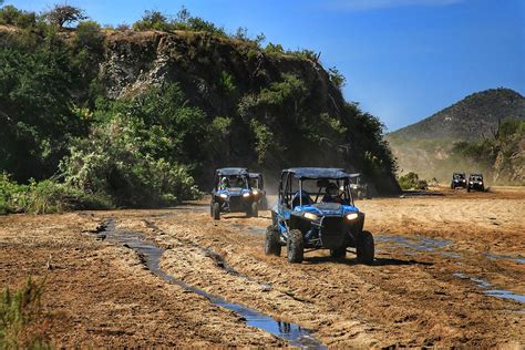 Three Atvs Driving Down A Muddy Dirt Road