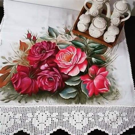 There Is A Table Cloth With Roses On It And Teapots In The Background