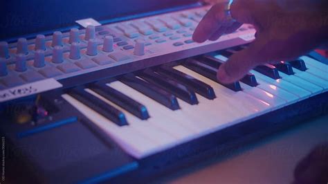 A Musician Playing Keyboards And Adjusting Knobs By Stocksy