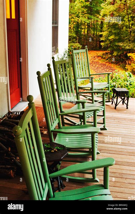 Green Rocking Chairs On Front Porch Of White Rural Farmhouse Stock