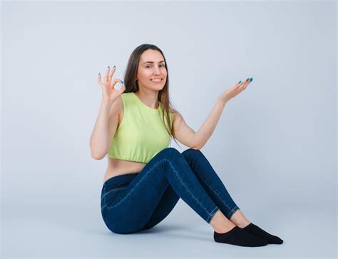 Une Fille Souriante Montre Un Geste Correct En S Asseyant Sur Le Sol