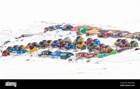 Multiple colorful Inuit houses and cottages on the hill covered in snow ...